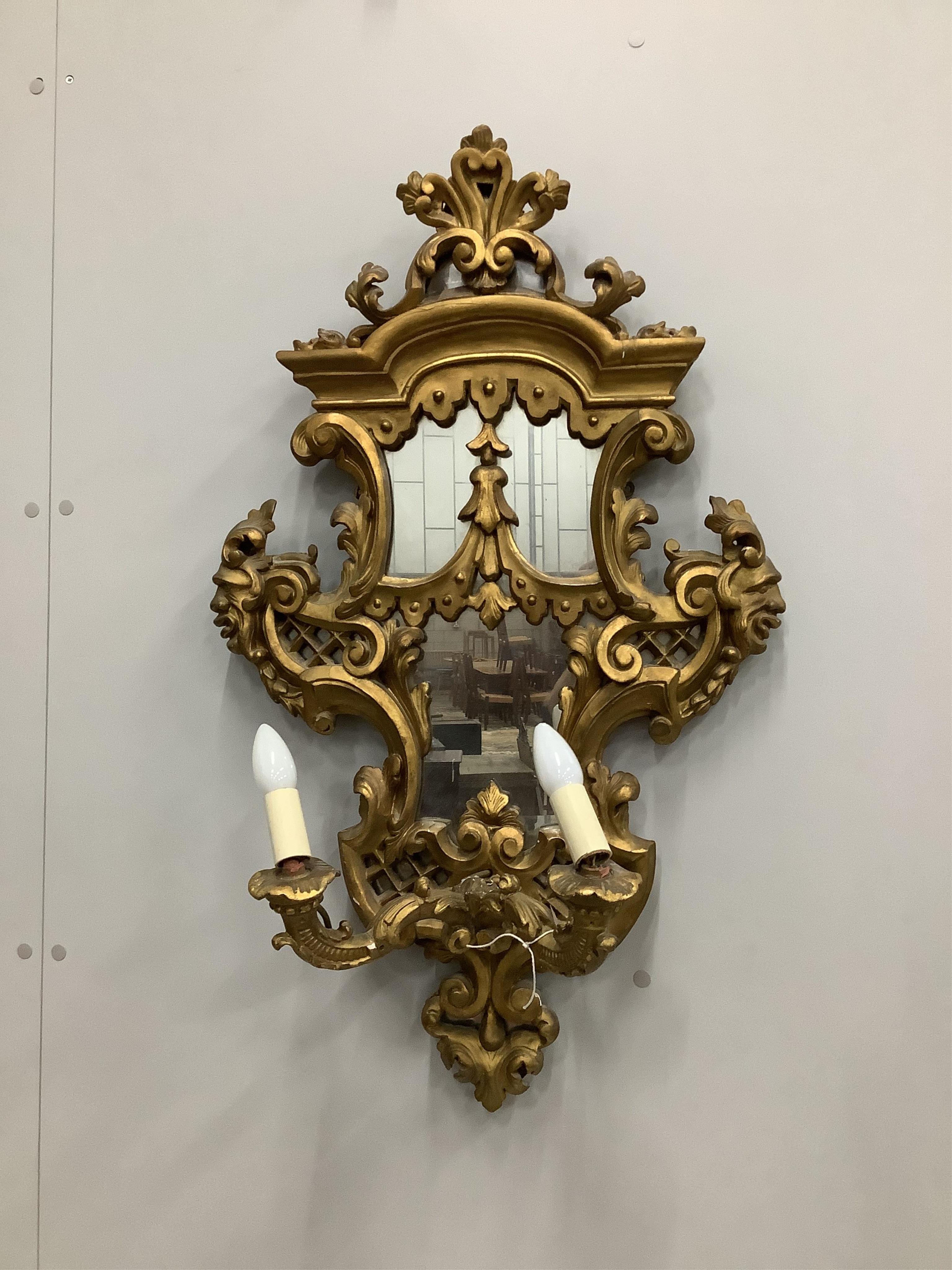 A pair of Italian style carved giltwood and composition two branch girandoles, width 52cm, height 86cm. Condition - poor